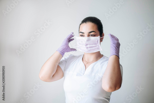 Female healthcare worker adjusting her protective face mask before beginning clinical duties.
