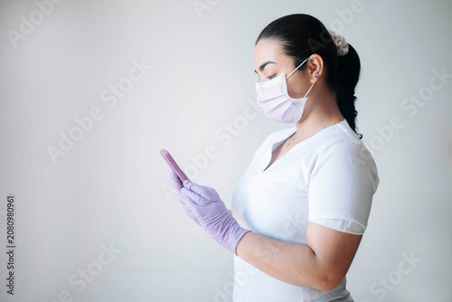 Female nurse reviewing medical information on a smartphone during her shift in a healthcare facility.