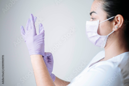 Female nurse adjusting protective medical gloves before performing a healthcare procedure.