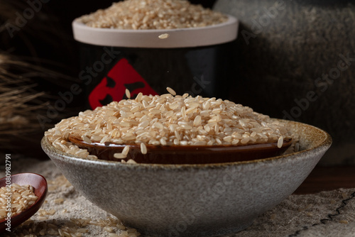 Uncooked Brown Rice in Ceramic Bowl with Wooden Spoon