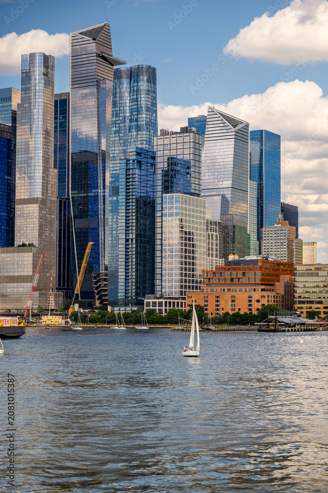 Fototapeta premium Sailboats near lightship on Hudson River, Manhattan skyline. Group of sailing vessels, red Frying Pan ship, glass skyscrapers, distant Empire State Building.