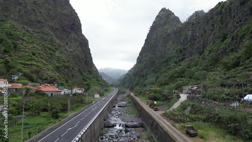 Low altitude aerial pull-away along highway and mountain valley river in Sao Vicente, Madeira