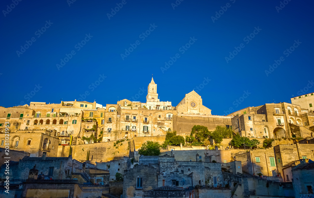 Fototapeta premium Matera. Panoramic view of golden hour sunset at Sassi di Matera in Italy, historic Sassi cave dwellings and ancient stone architecture in Basilicata