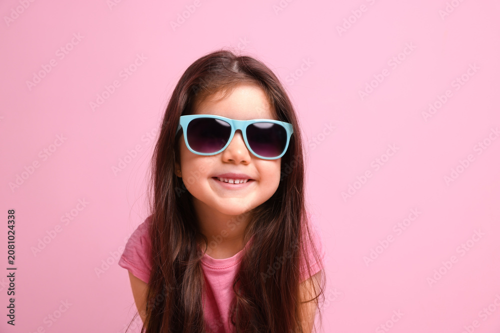 Fototapeta premium Cute little girl in sunglasses on pink background