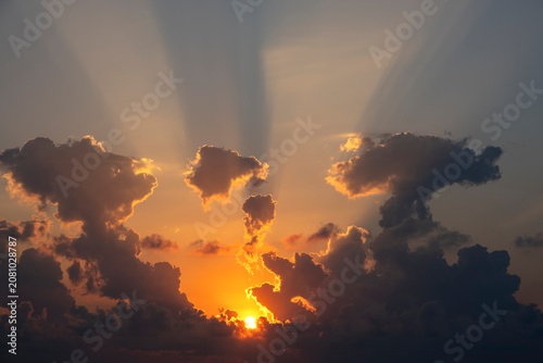 Schilderij op canvas Sun setting behind clouds with dramatic golden crepuscular light rays