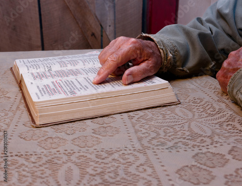 Fotografi A work worn hand tracing the lines of scripture in the family Bible
