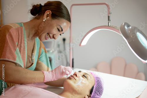 Aesthetician applying facial mask on woman in beauty spa