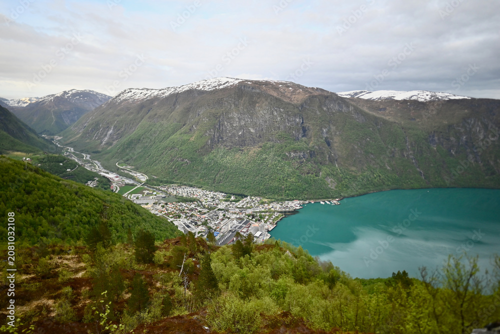 Obraz premium Panoramic view of Høyanger, Norway from a mountain above the fjord, showing the town, valley, turquoise water, and surrounding rocky cliffs.