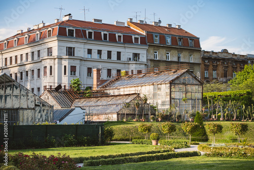 Old, rusty greenhouses in the botanical garden in the centre of Zagreb city, Croatia, with old apartment blocks in the background