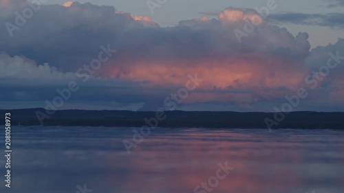 Surface of the river with calm waves and pink clouds in the sky