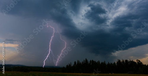 Tableau sur toile Powerful forked lightning strike illuminating dramatic storm clouds behind a for