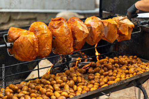 Cuadro en lienzo Roasting pork hocks and potatoes on a rotisserie at a street event