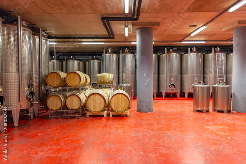 Slika na platnu Stainless steel tanks and oak barrels in wine cellar