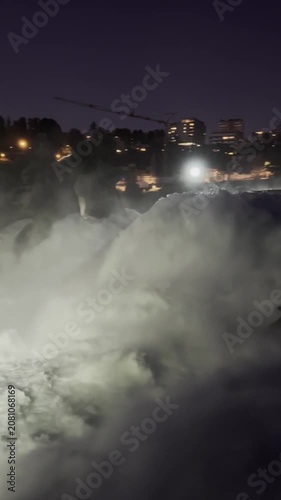 SCHAFFHAUSEN, SWITZERLAND - OCTOBER 11, 2025: Night view of the illuminated Rhine Falls with powerful cascading water and city lights surrounding the famous natural landmark.