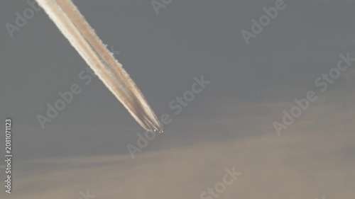 Four engine jet leaving colorful contrail at sunset