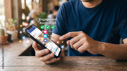 A man uses a modern black smartphone to engage with digital social media marketing analytics displayed as vibrant floating icons above the bright touchscreen interface
