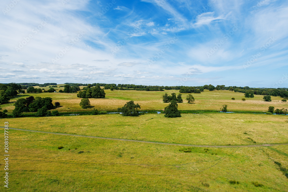 Fototapeta premium Aerial landscape over rural fields with trees and blue sky, UK
