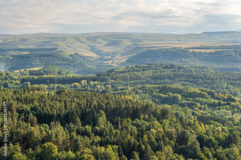Obraz premium Layers of green mountains and hills in the haze during sunset. Panoramic View of Green hills and Meadow.