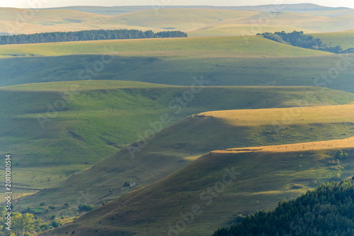 Layers of green mountains and hills in the haze during sunset. Panoramic View of Green hills and Meadow.