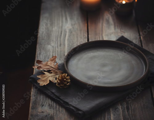 Empty Dark Ceramic Plate with Autumn Decoration on Rustic Wooden Table for Seasonal Dinner Setting