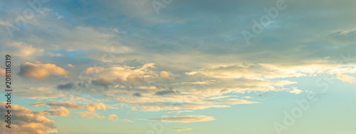Beautiful sunset sky background with dramatic golden light on soft cumulus clouds for panoramic travel mockup design