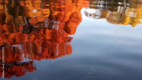 Reflective water surface mirrors vibrant autumn foliage, creating abstract color gradients