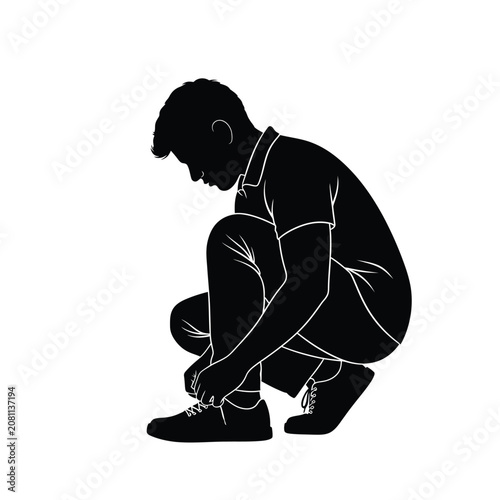 Young man crouching down to tie his shoelaces in silhouette