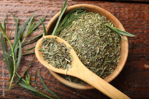 Fotografie Dry tarragon in bowl, spoon and fresh leaves on wooden table, flat lay