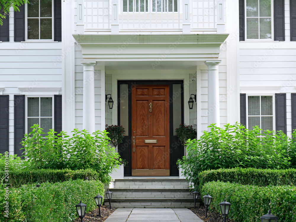 Obraz premium House with white siding and elegant portico entrance and wood grain front door