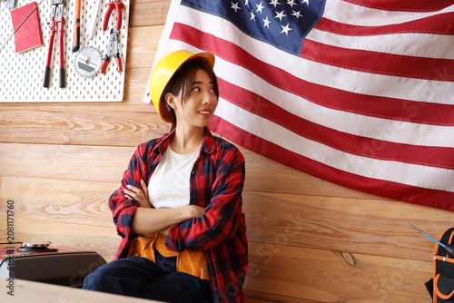 Female Asian worker near USA flag in workshop. Labour Day celebration