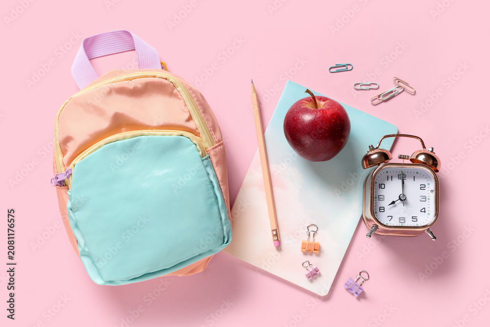 Obraz premium Tasty apple, alarm clock, backpack and different school stationery on pink background