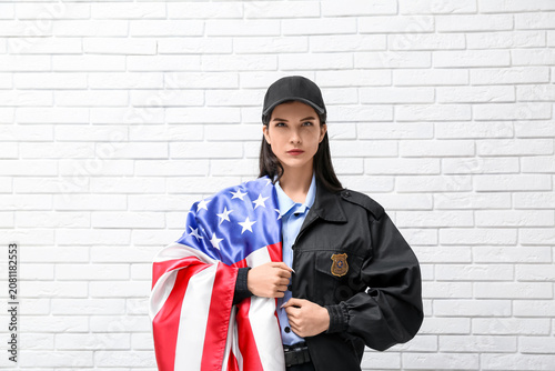Фотография Female police officer with USA flag on white brick background