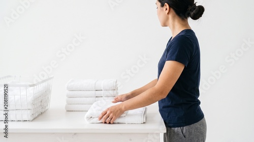 Photorealistic person from side, no face visible, folding towels neatly, bathroom chore, white seamless background