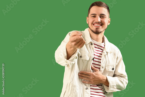 Konstfotografi Laughing young man pointing at viewer on green background