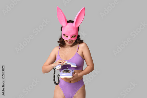 Beautiful young Asian woman in bunny mask and sexy lingerie with retro teleph...