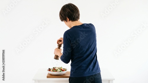 Photorealistic person viewed from behind, no face visible, grinding pepper over dish, simple action, white isolated background