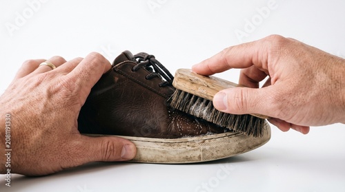 Photorealistic close-up hands cleaning shoes with brush, care detail, no face, white seamless isolated background