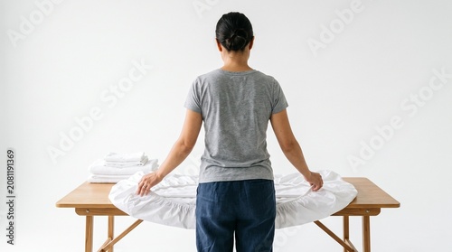 Photorealistic person viewed from behind, no face, folding fitted sheets, fabric handling, clean white isolated backdrop