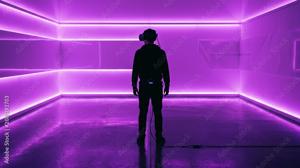 Fototapeta premium Silhouette of a person walking in a futuristic neon-lit corridor.