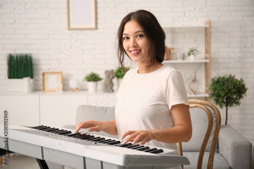 Young woman playing synthes...
