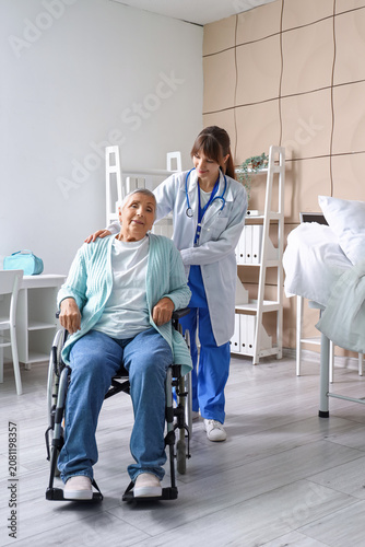 Senior woman in wheelchair with doctor at nursing home