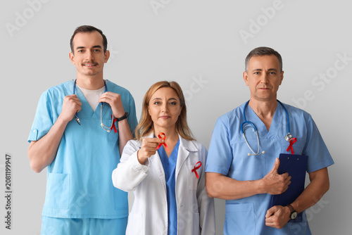 Professional team of doctors with red ribbons on grey background. World AIDS ...