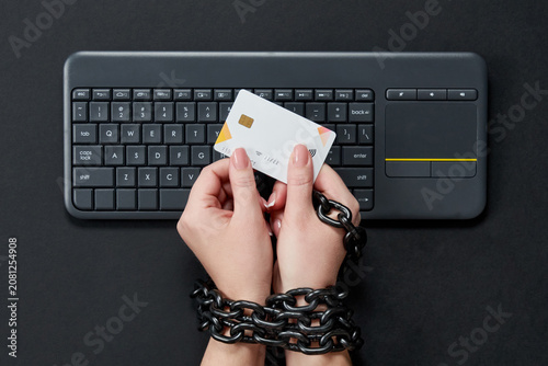 Bild auf Leinwand Woman with metal chain holding credit card over keyboard, online shopping addict