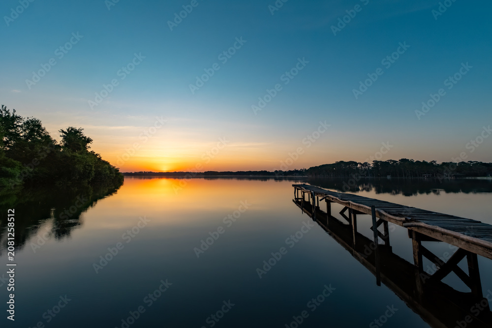 Obraz premium Sunset over a lake with a dock