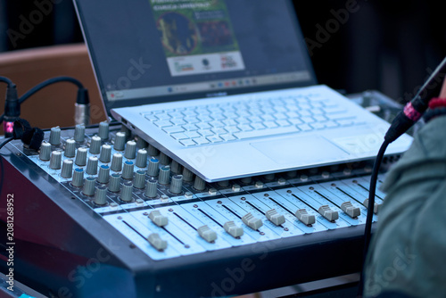 Fotografie Silhouette of a man behind a soundboard and computer, managing and monitoring th