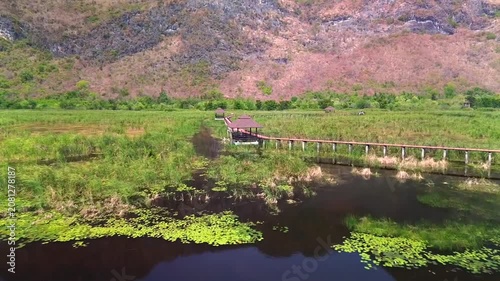 A low drone flight over a lake, a bridge, among houses and a tower