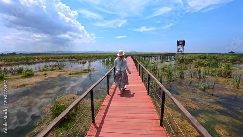 a girl walks across a bridge in the middle of a lake