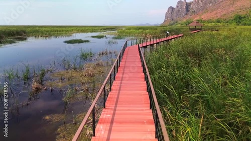 Two people holding hands and walking on a bridge in the middle of a lake, filmed with a drone