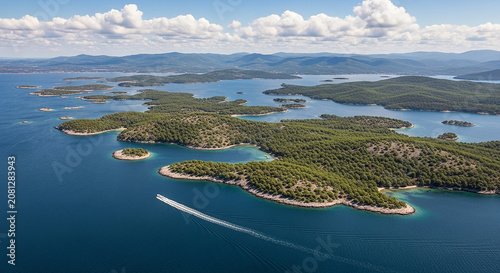 Aerial view of a green island and blue ocean with a boat leaving a wake