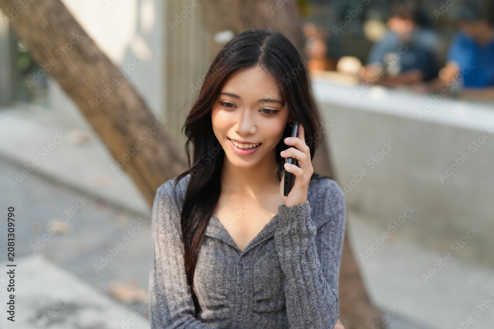 Fototapeta premium Asian girl using smartphone talking with friend at outdoor